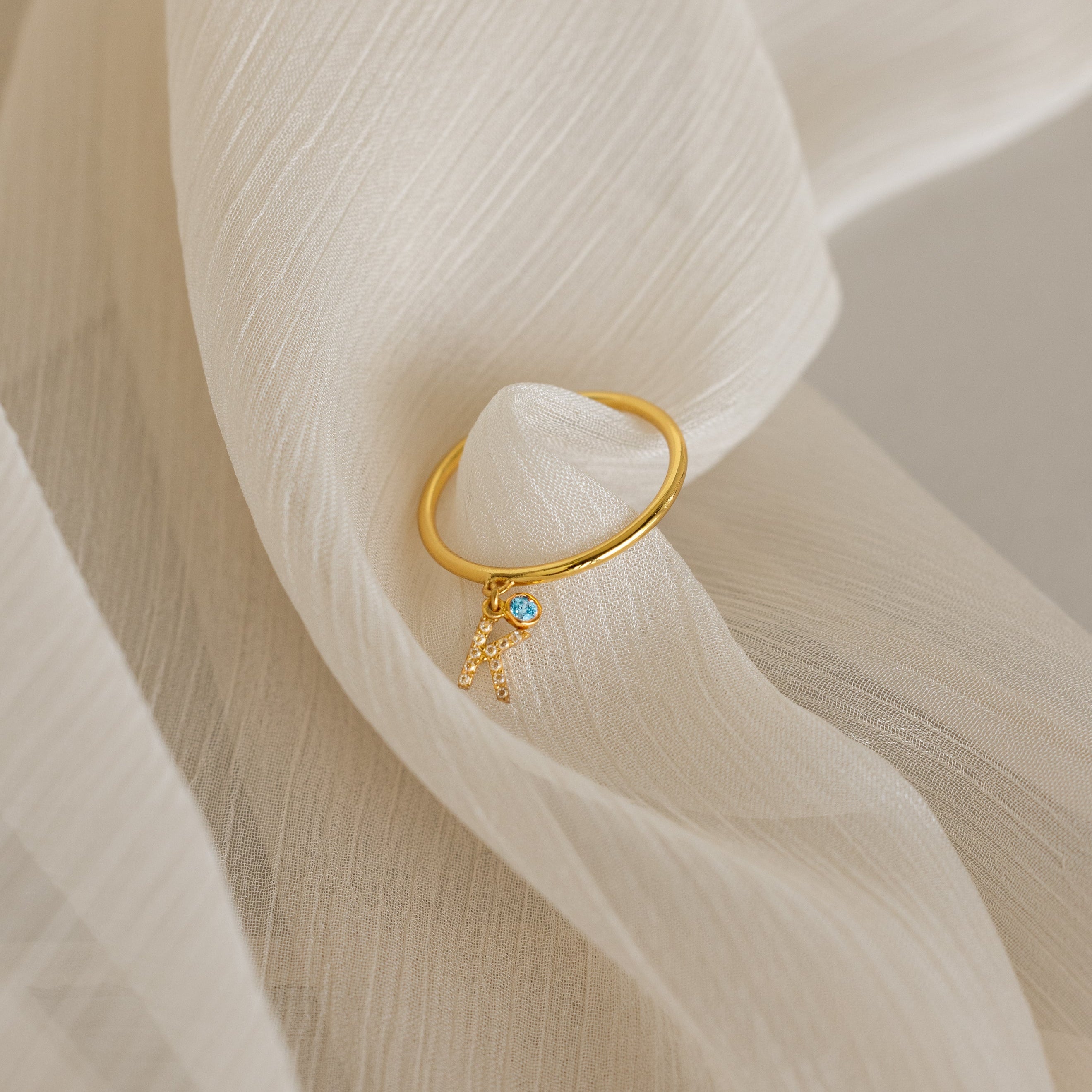 Gold ring with a blue gemstone on a soft beige fabric background