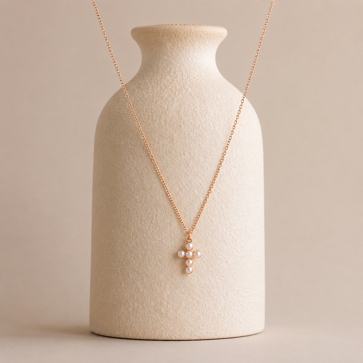 Delicate necklace with a small pendant on a beige vase against a beige background