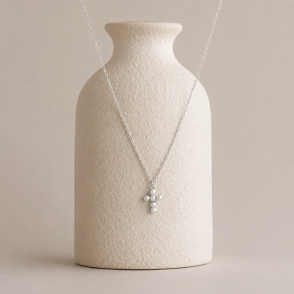 Necklace with a pendant on a textured beige vase against a plain background