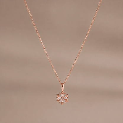 Rose gold necklace with a snowflake pendant on a brown background