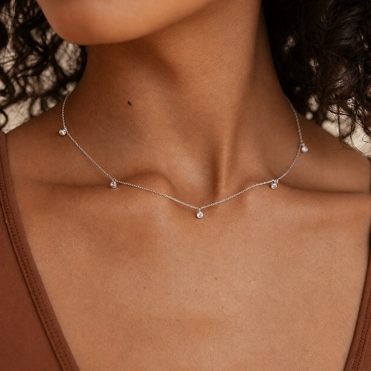 Necklace with small beads on a person wearing a brown top