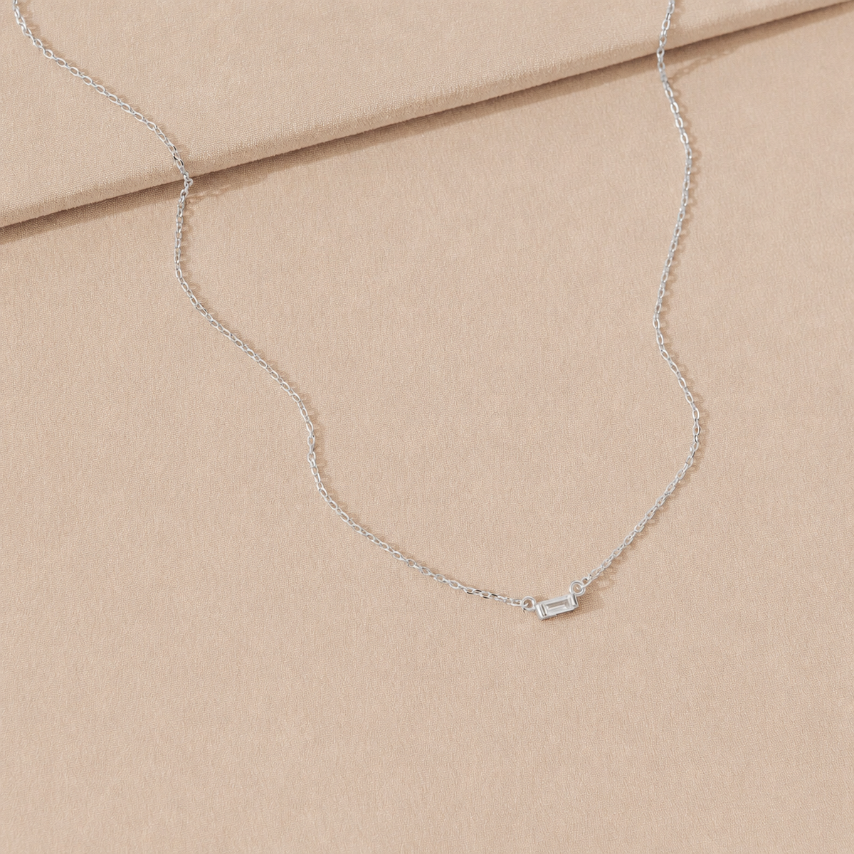 Silver necklace on a beige fabric background