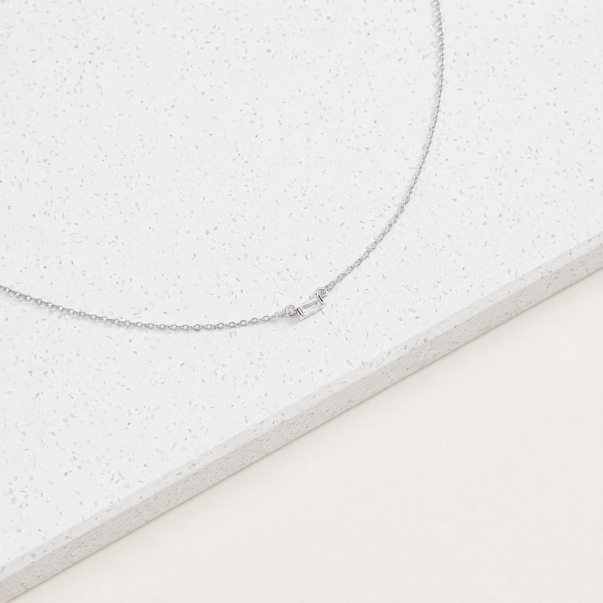 Silver necklace on a textured white surface