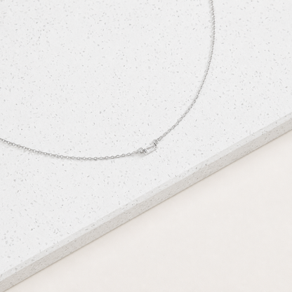 Silver necklace on a textured white surface