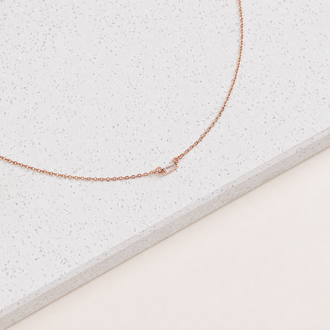 Rose gold necklace on a textured white surface