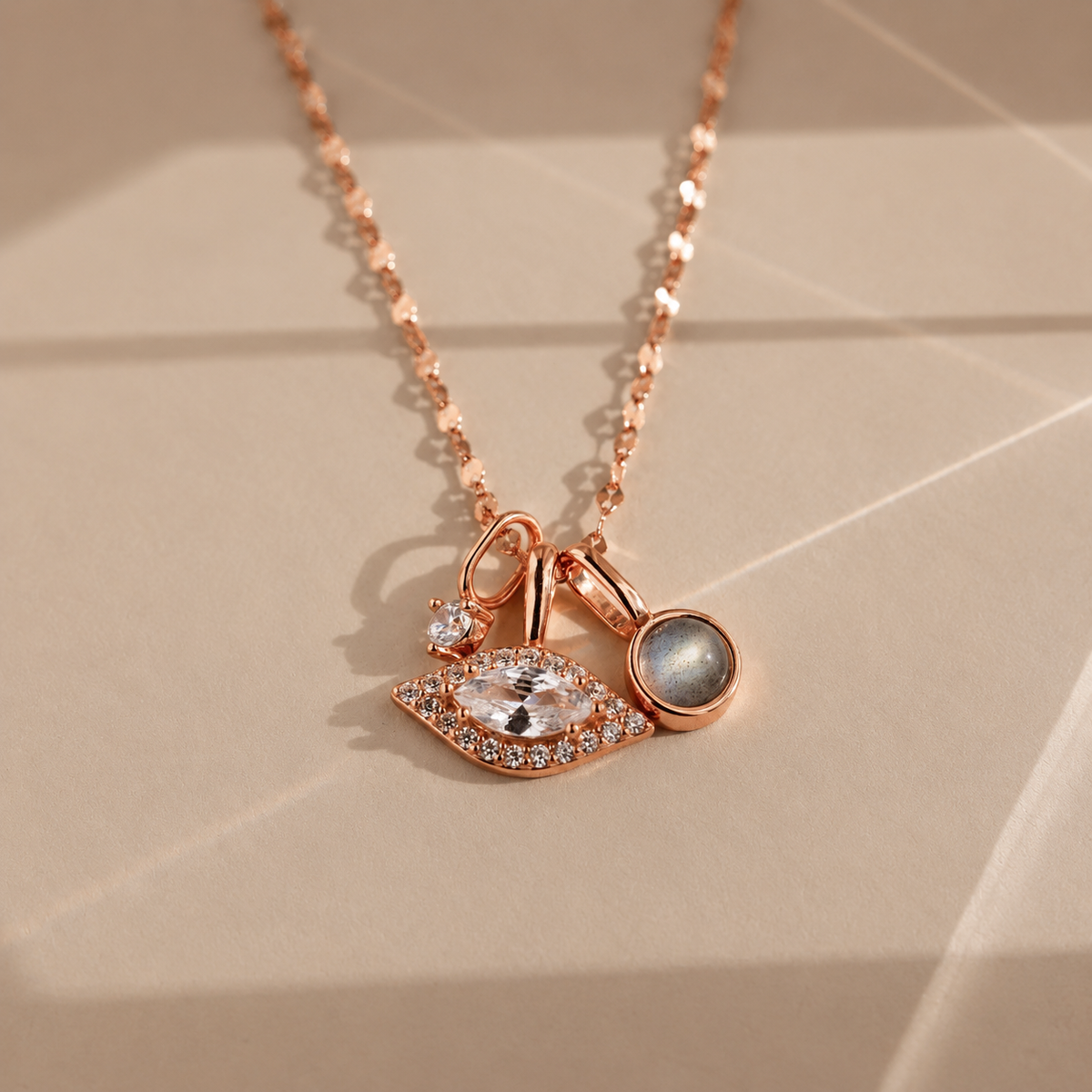 Rose gold necklace with eye-shaped pendant on a beige background