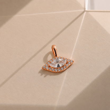 Rose gold pendant with a clear gemstone on a beige surface