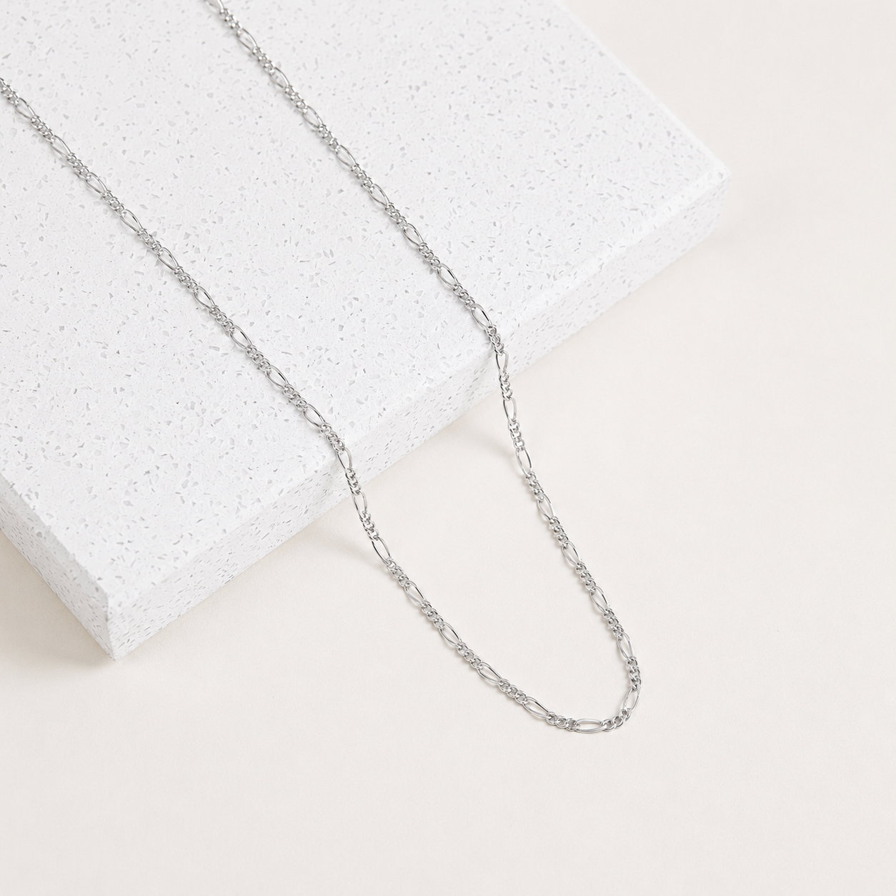 Silver chain necklace on a light gray background