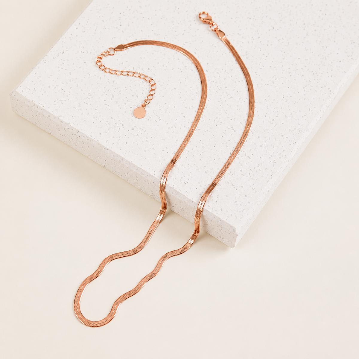 Rose gold necklace on a textured white surface