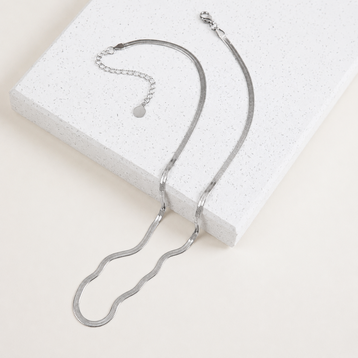 Silver necklace on a textured white surface