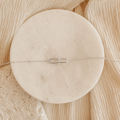 Silver bracelet on a round beige stone with a natural wood background