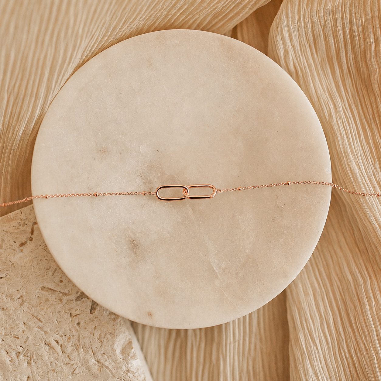 Rose gold bracelet on a round beige stone surface