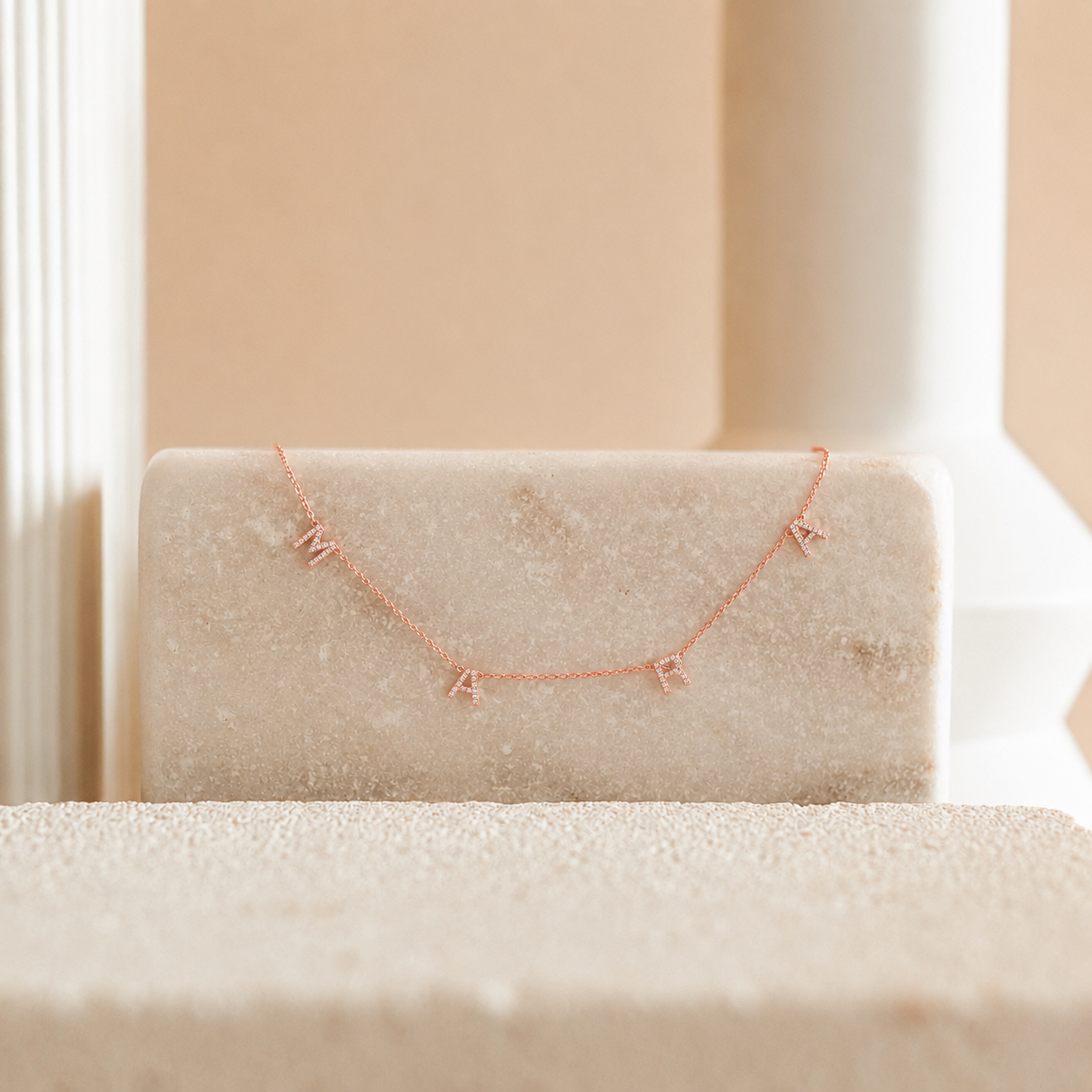 Rose gold necklace on a beige cushion with a soft background