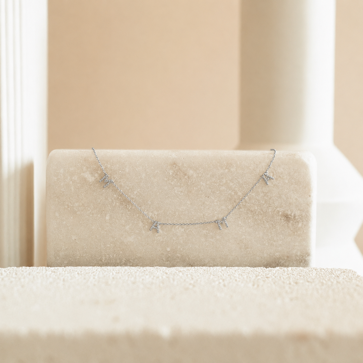 Silver necklace on a beige cushion with a neutral background