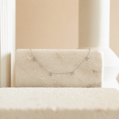 Silver necklace on a beige cushion with a neutral background