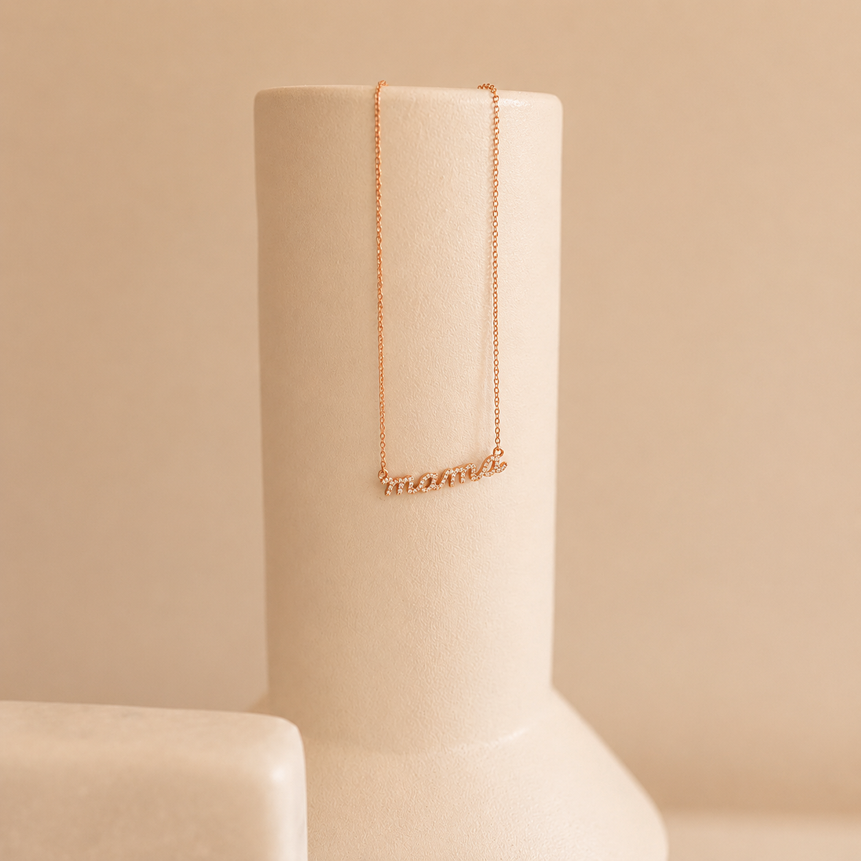 Rose gold necklace on a beige stand against a beige background