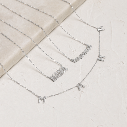 Silver necklace with letter pendants on a textured surface