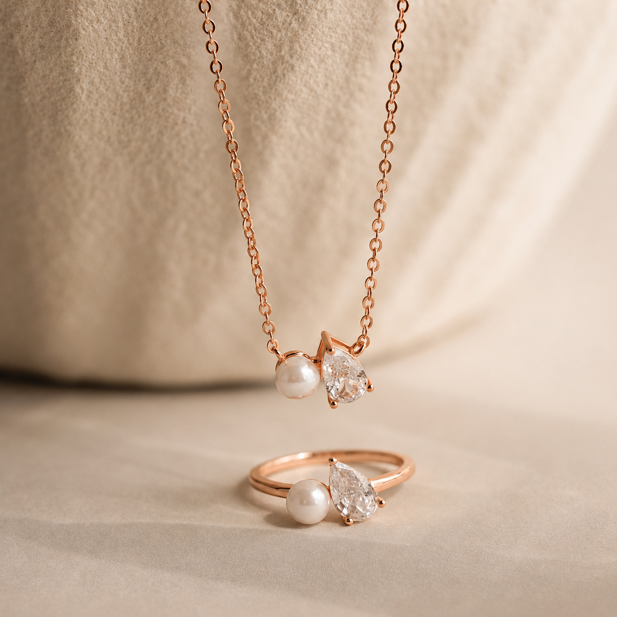 Rose gold necklace and ring set with pearls and diamonds on a beige background