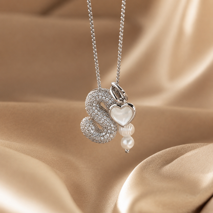 Silver necklace with heart and pearl pendant on a beige fabric background