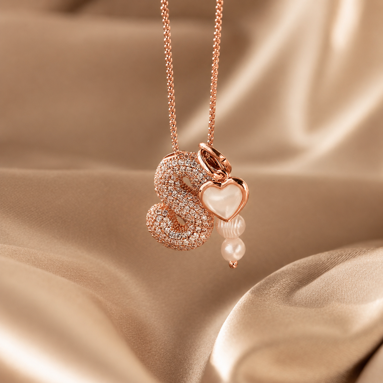 Rose gold necklace with heart pendant on a beige fabric background