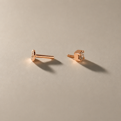 Rose gold earrings with small diamonds on a beige background