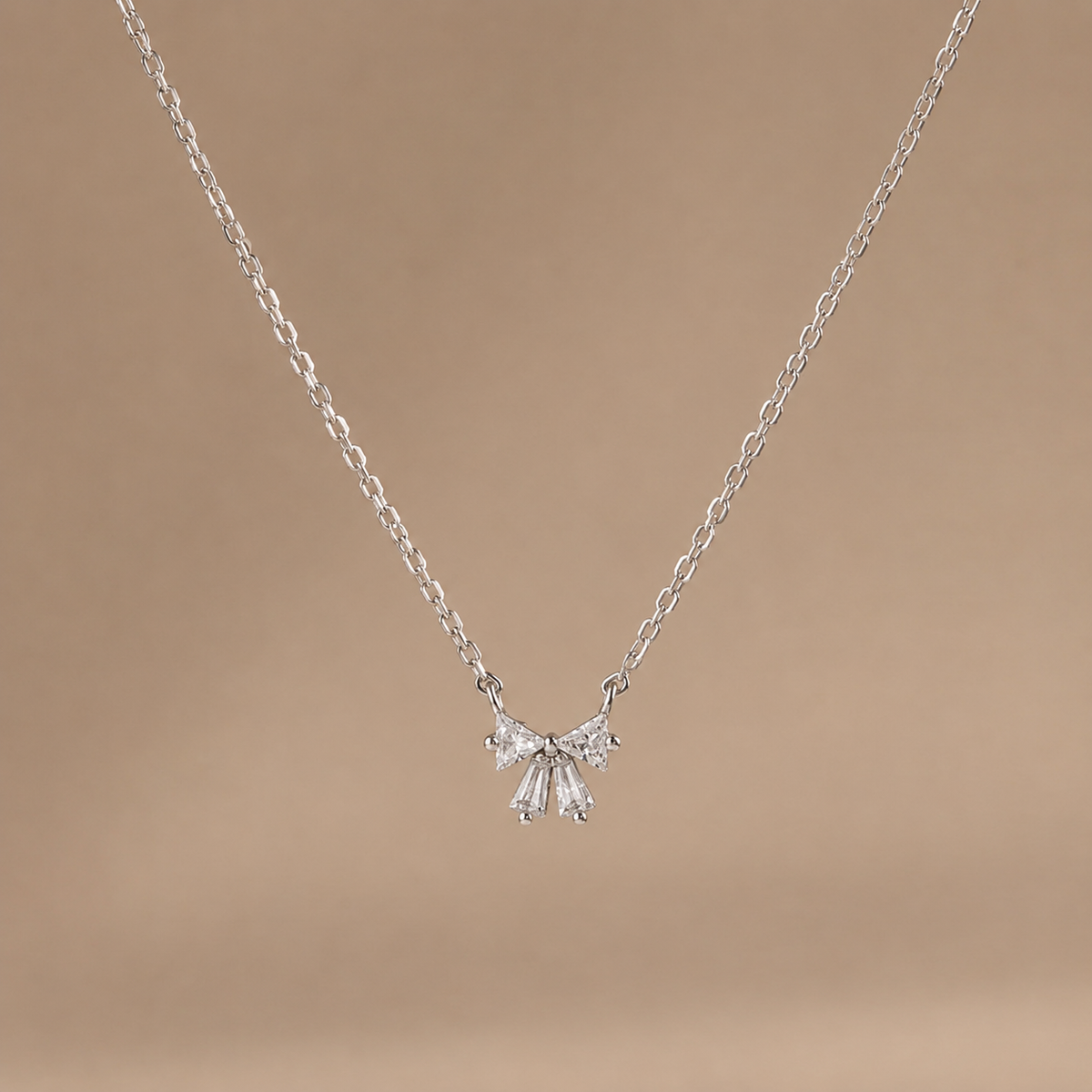 Silver necklace with a delicate pendant on a brown background