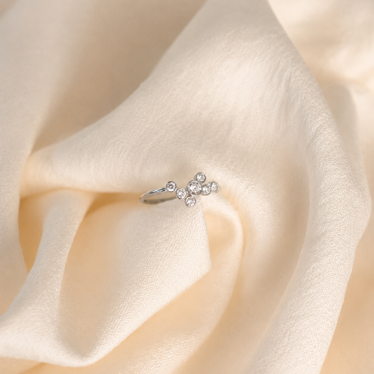 Silver ring with diamonds on a soft beige fabric background