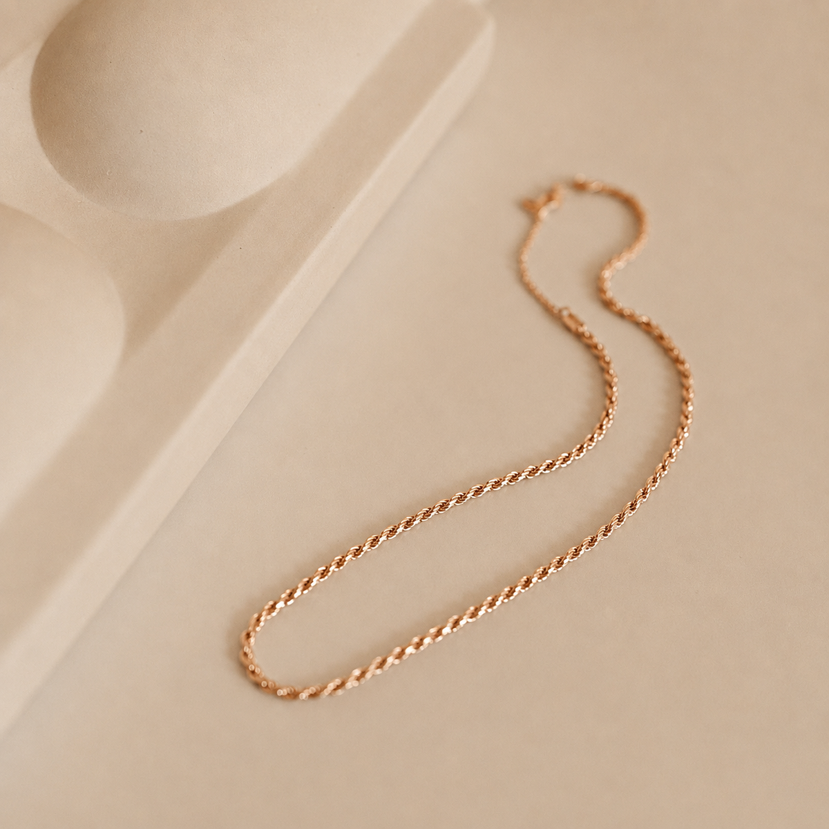 Gold chain necklace on a beige background