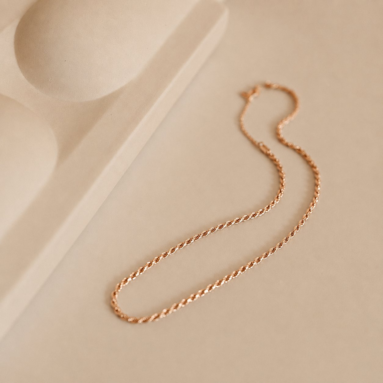 Gold chain necklace on a beige background