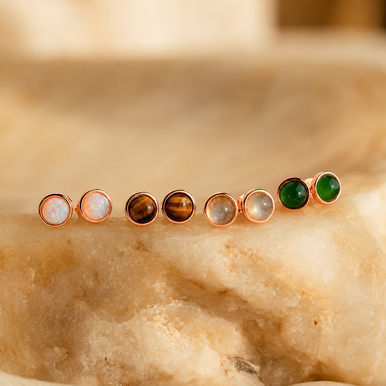 Set of gemstone stud earrings on a marble surface