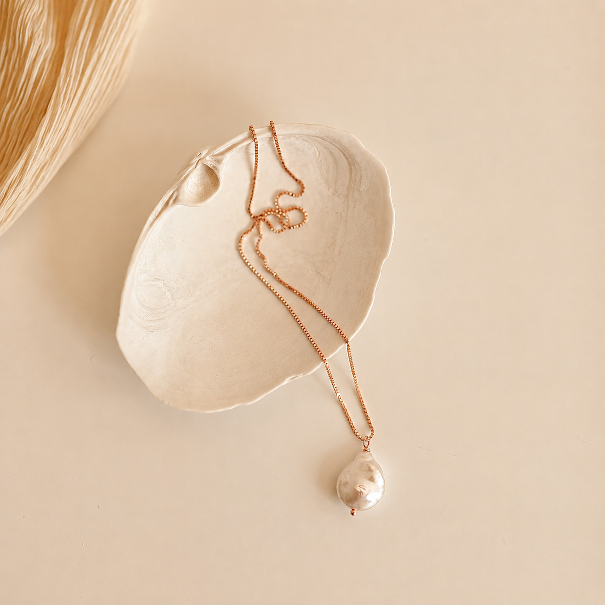 Pearl necklace with a pendant on a beige shell against a beige background