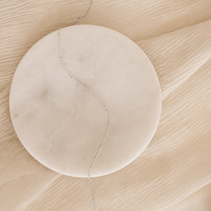 Round beige object with a thin string on a beige surface