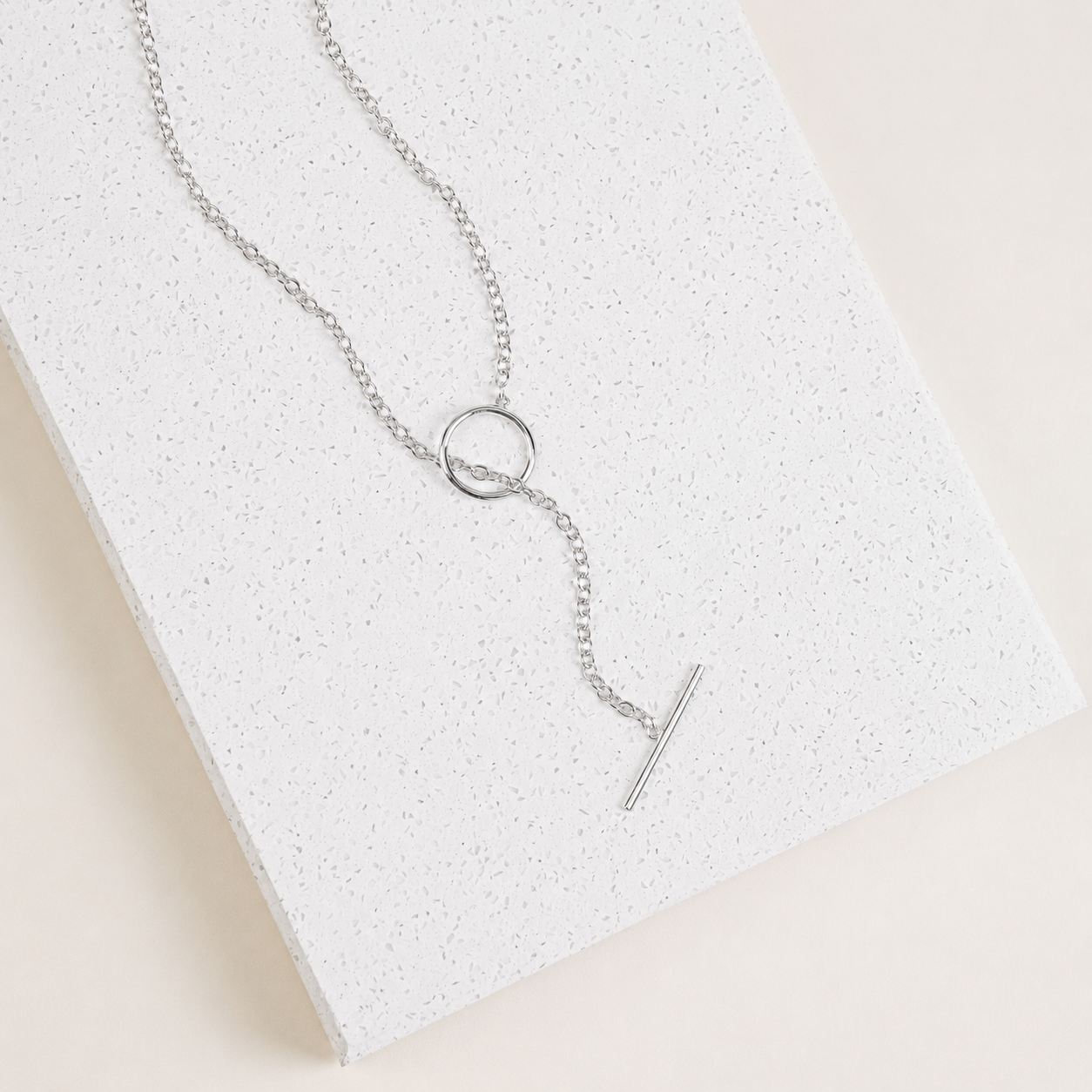 Silver necklace with a unique pendant on a textured white surface