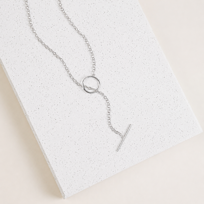 Silver necklace with a unique pendant on a textured white surface