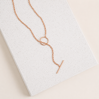 Rose gold necklace with a unique pendant on a textured white surface