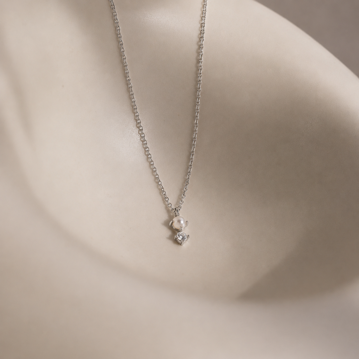 Delicate silver necklace with a heart-shaped pendant on a neutral background