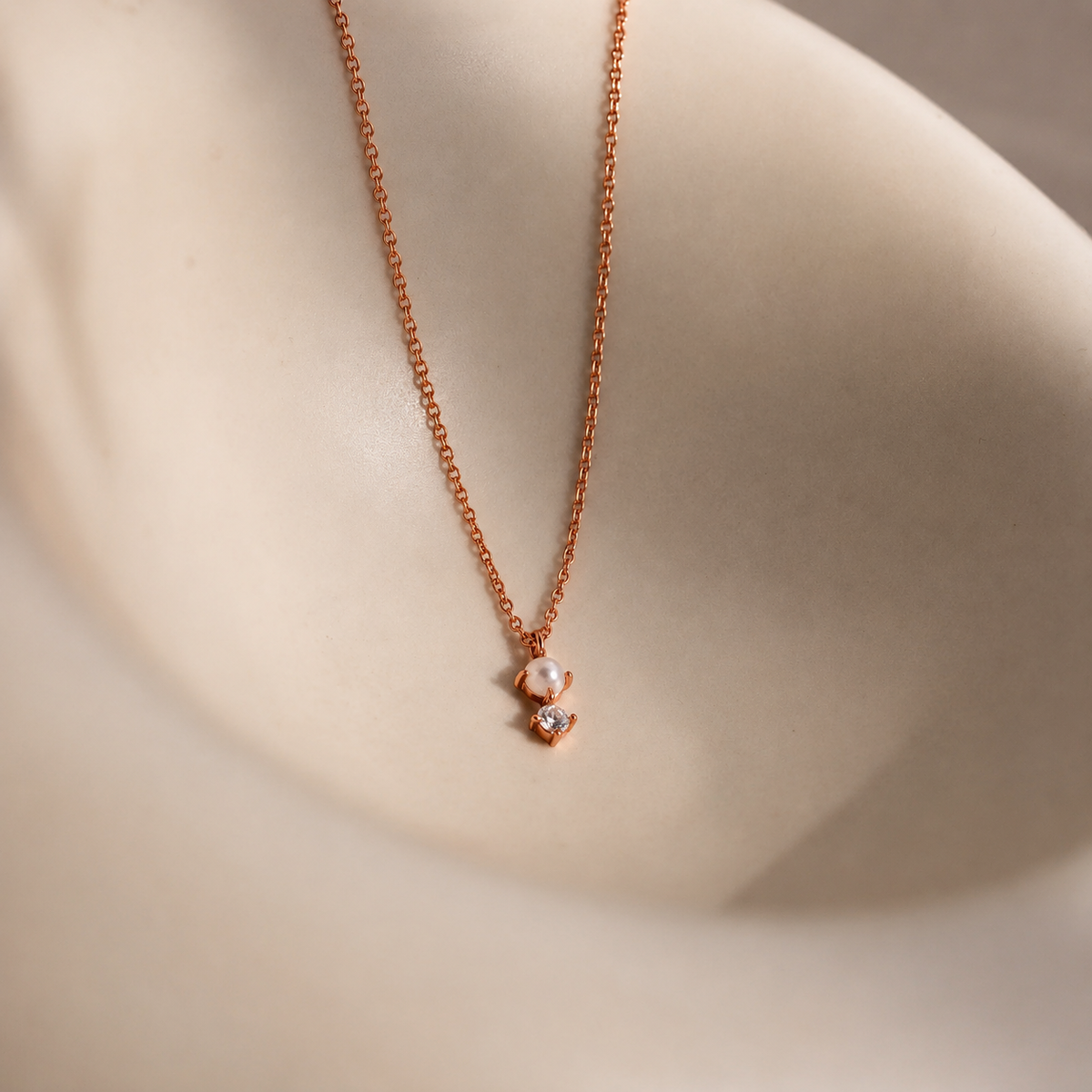 Rose gold necklace with a heart-shaped pendant on a neutral background