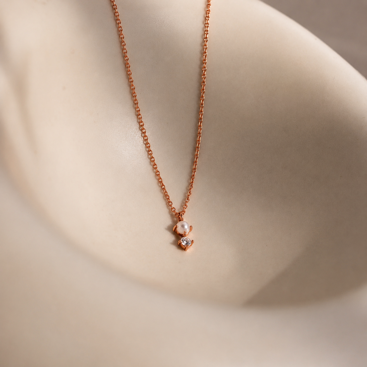 Rose gold necklace with a heart-shaped pendant on a neutral background