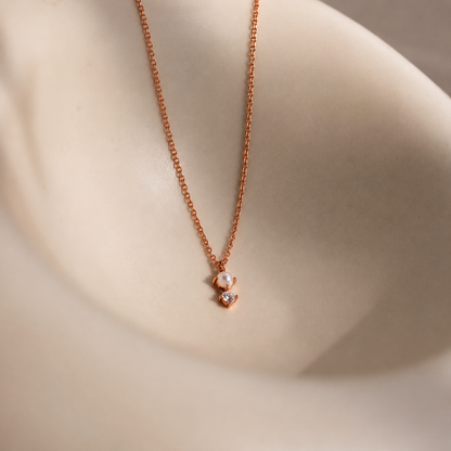 Rose gold necklace with a heart-shaped pendant on a neutral background