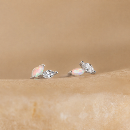 Pair of opal and silver stud earrings on a beige background