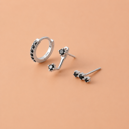Silver earring set with black gemstones on a beige background