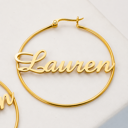 Gold hoop earrings with 'Lauren' engraving on a light background