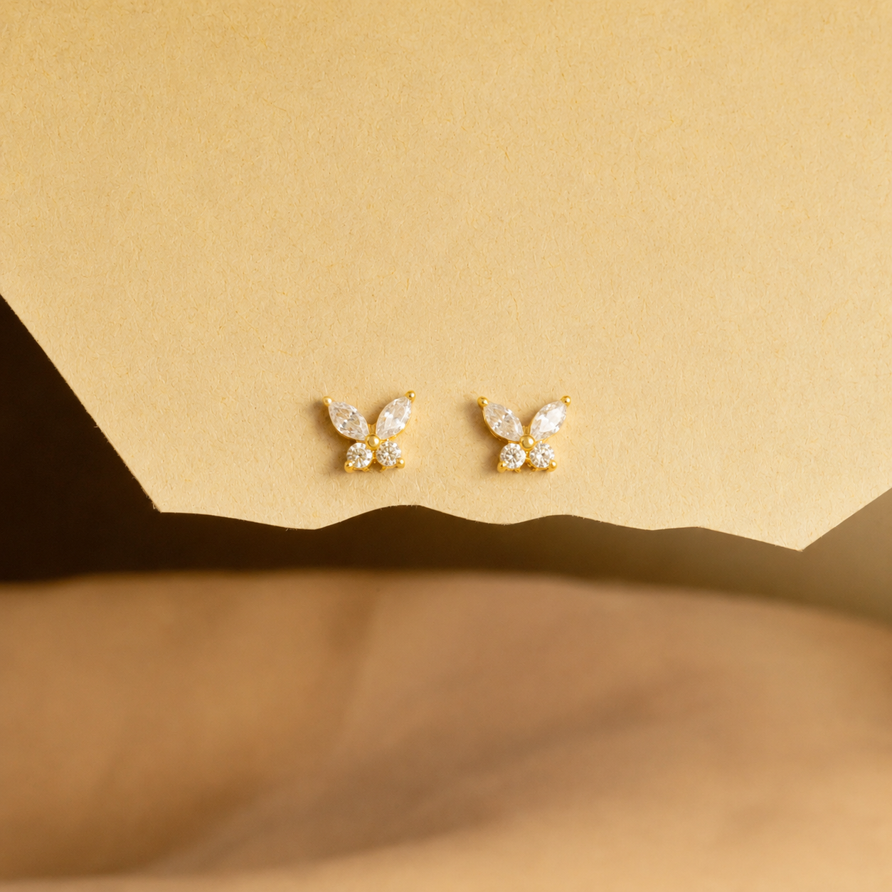 Butterfly-shaped earrings on a beige background