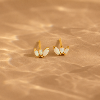 Gold earrings with opal stones on a beige background