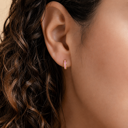 Close-up of an ear wearing a pink hoop earring with wavy hair.
