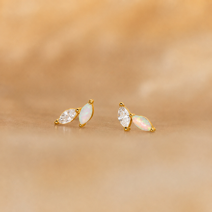 Pair of gold earrings with opal stones on a beige background