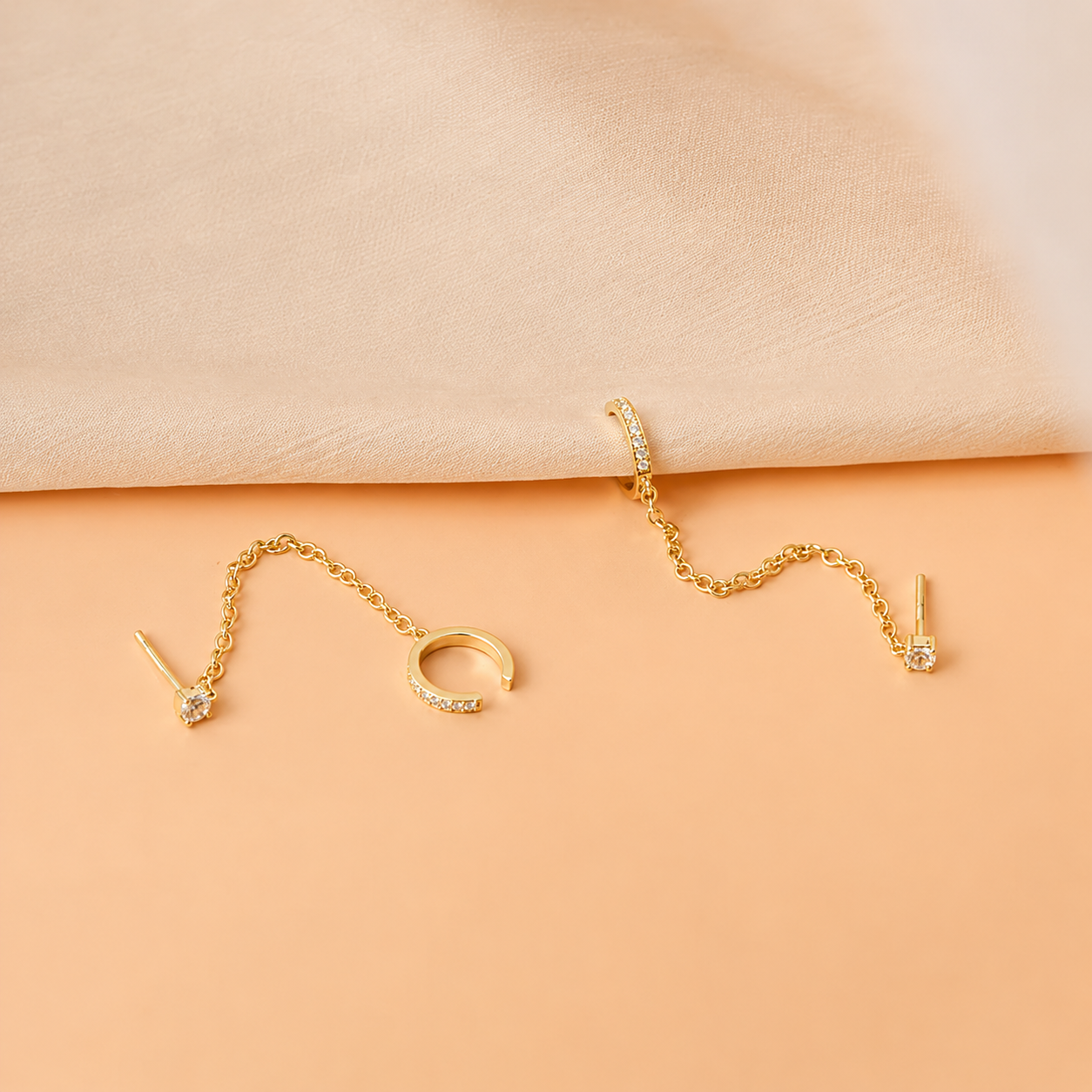 Gold jewelry set on a peach-colored fabric background