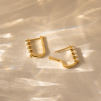 Gold hoop earrings on a textured gold surface