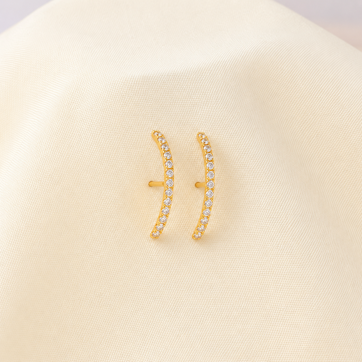 Gold earrings with small diamonds on a beige background