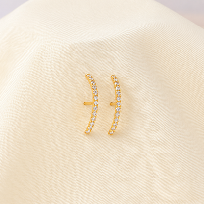 Gold earrings with small diamonds on a beige background